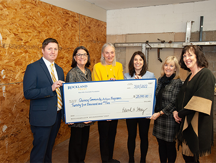 Rockland Trust's Charitable Giving team and members of the Quincy Action Programs posing with a giant check.